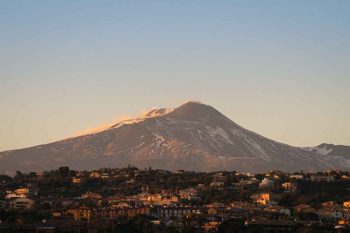 Le volcan enneigé de l'Etna dominant les toits de Catane au coucher du soleil, Sicile, Italie