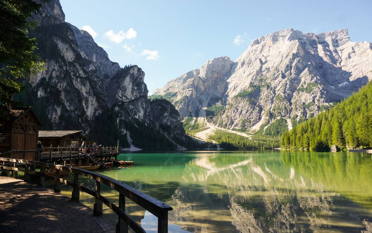 Emerald-green Lago di Braies with wooden boathouse and dramatic Dolomite peaks reflected in the water, South Tyrol, Italy