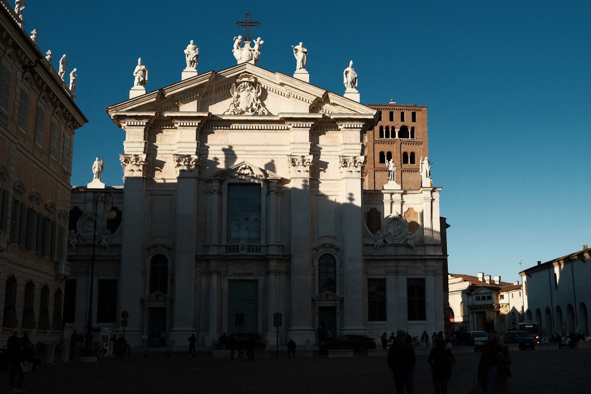 Mantua Cathedral baroque facade with statues on top and the Palazzo Ducale tower alongside, Piazza Sordello, Mantova, Lombardy, Italy