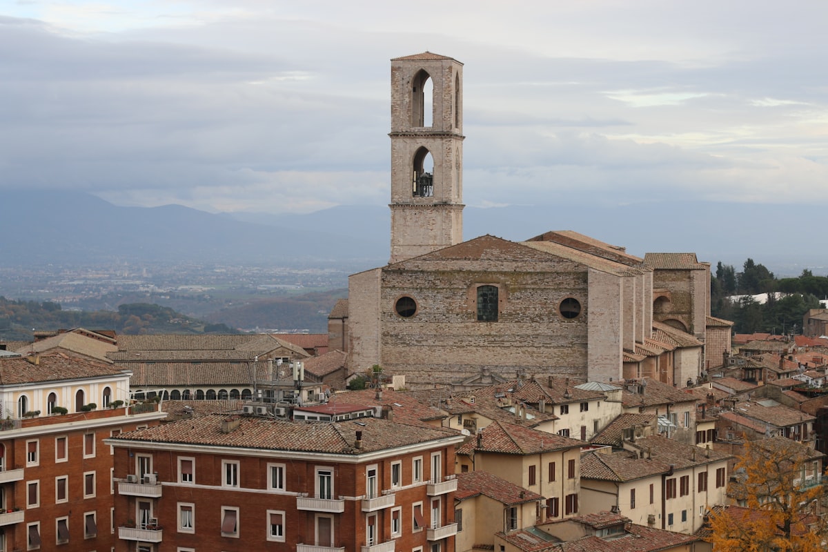 Perugia bell tower rising above terracotta rooftops with the Umbrian valley and mountains beyond, Italy