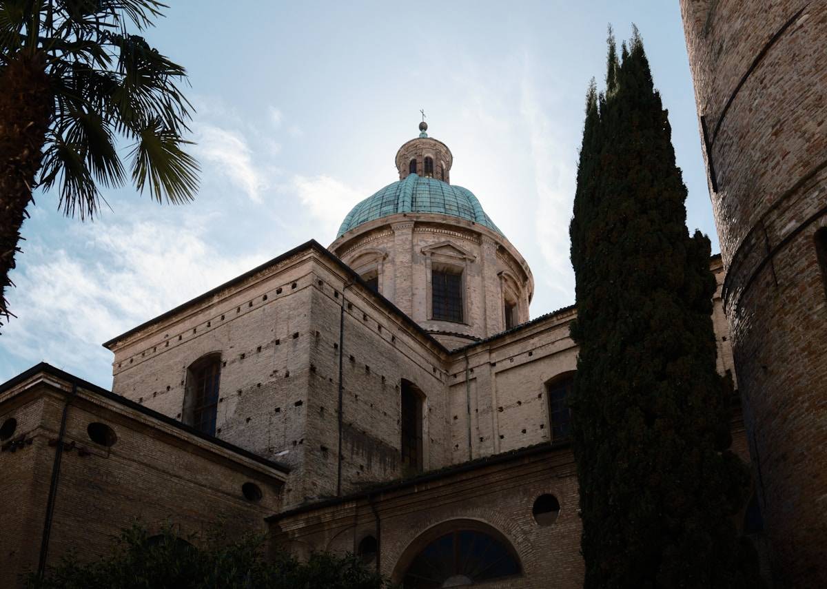 Baroque church dome with blue-green copper roof rising above brick buildings, Ravenna, Emilia-Romagna, Italy